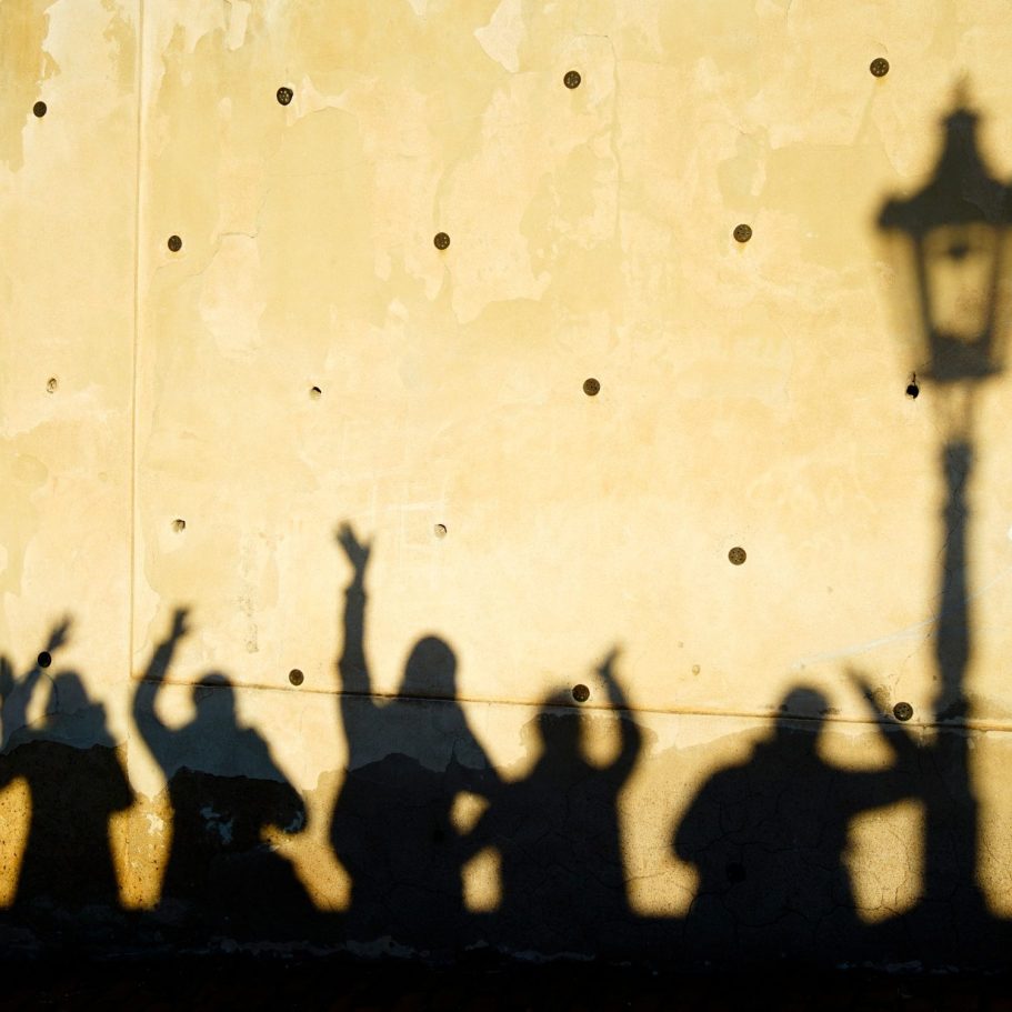 Fotoworkshops und Fotoreisen Silhouetten einer Reisegruppe vor einer sonnigen Wand mit Laterne