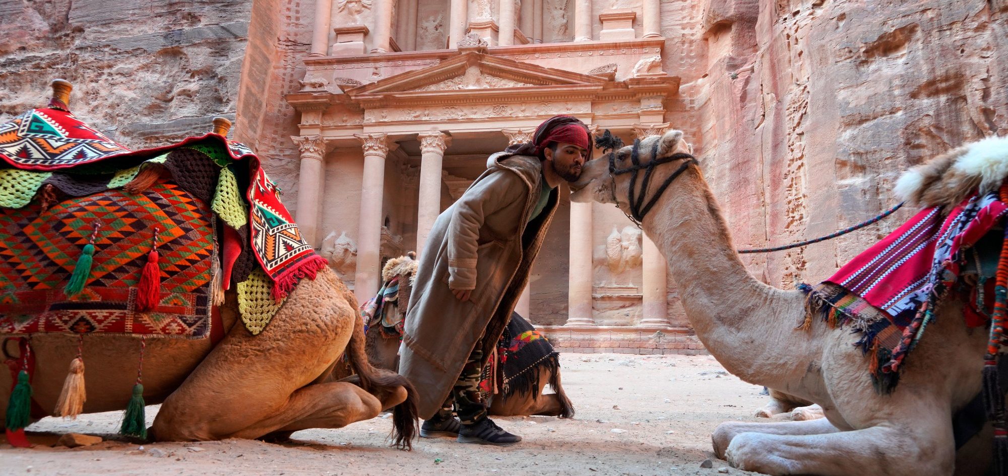 Reisefotografie in Petra, Jordanien Kameltreiber mit zwei geschmückten Dromedaren vor dem Schatzhaus von Petra
